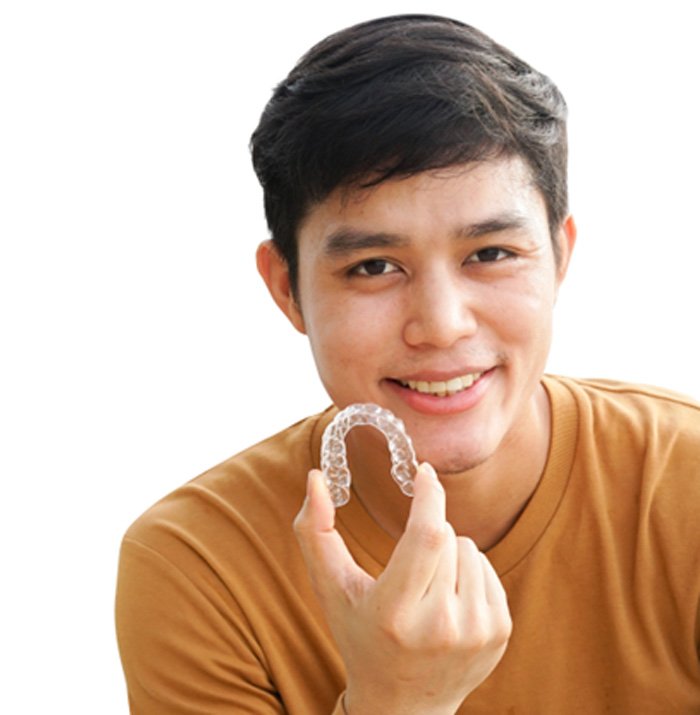 Young man in orange shirt holding Invisalign aligner