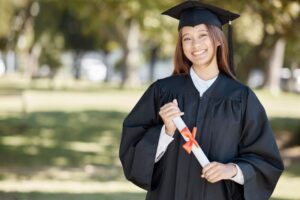 Smiling graduate in cap and gown holding her diploma