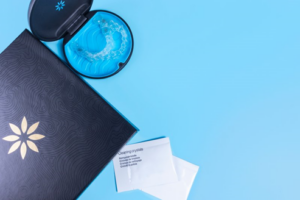 Invisalign case, trays, and cleaning crystals sitting on blue surface